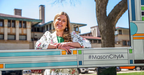 a woman posing for a photo near signage that touts Mason City