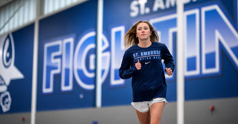 Woman in long-sleeved shirt runs on indoor track