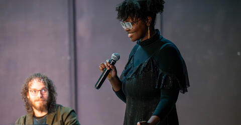 playwright Cianon Jones holds a microphone during a public staged reading of her play