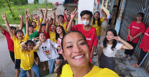University of Iowa gymnast Adeline Kenlin posing for a selfie with youth in Vietnam