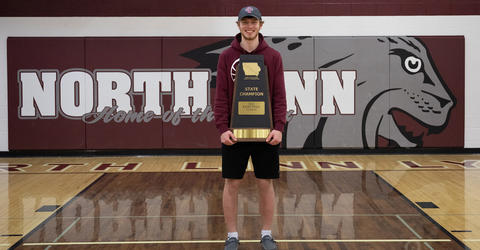 North Linn student Dylan Kurt stands in gymnasium holding state championship trophy
