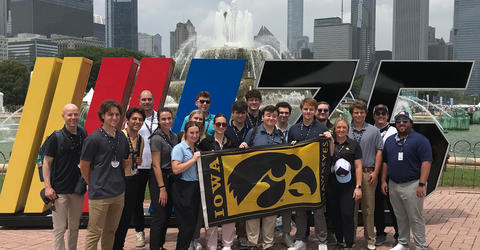 University of Iowa students posing for photo in Chicago, holding a flag with a Tiger hawk