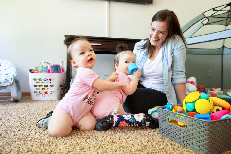 twin girls cling to their mother in the family's home
