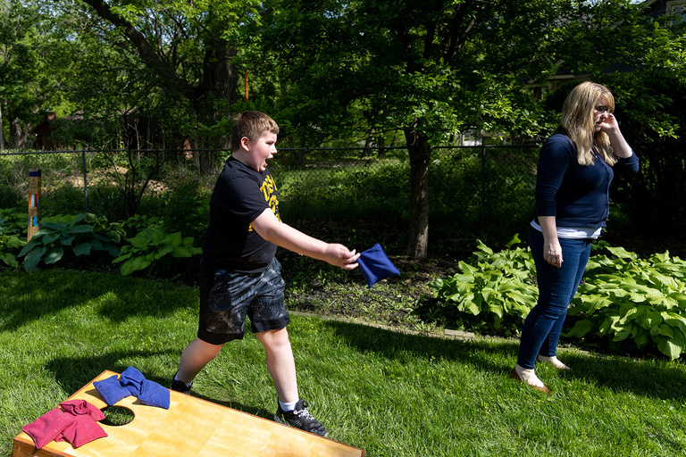 A boy outside playing cornhole