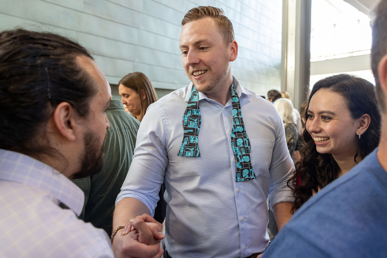A man with a silly tie shaking someones hand