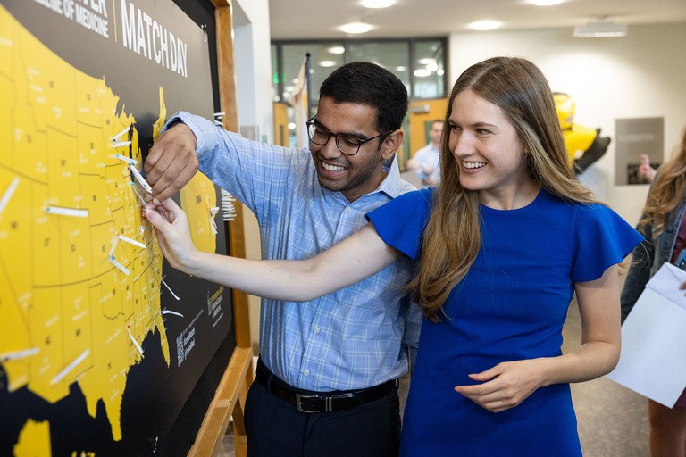 Two people putting papers on a map of the united states
