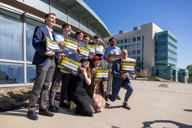 A group of people smiling and holding up their signs