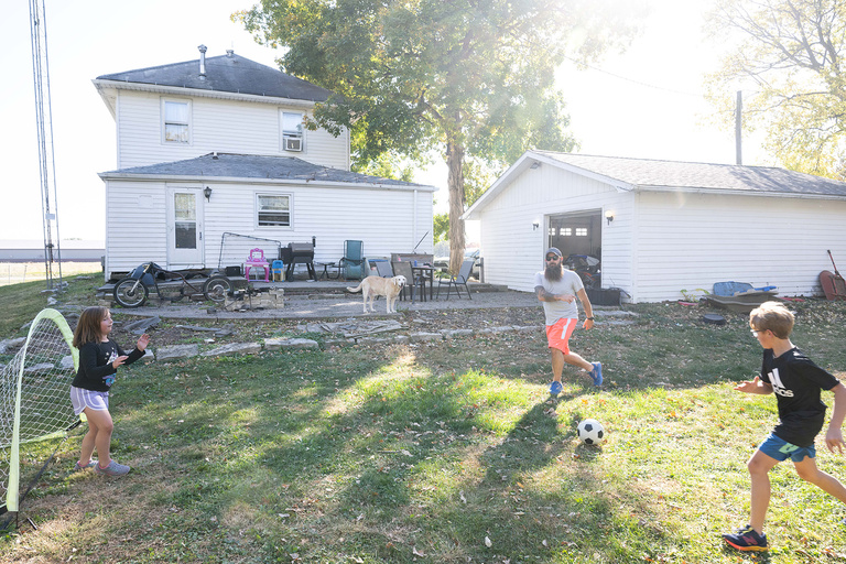 a dad and his kids playing soccer in their yard