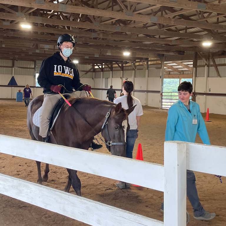 a young boy riding a horse at a stable