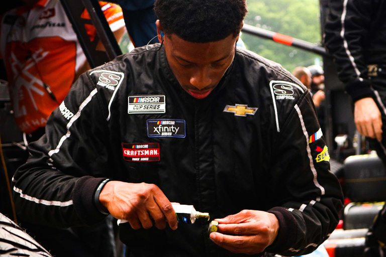 a man examining something in pit row at a nascar race