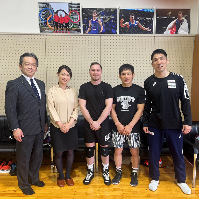 five people standing in front of a wall and smiling