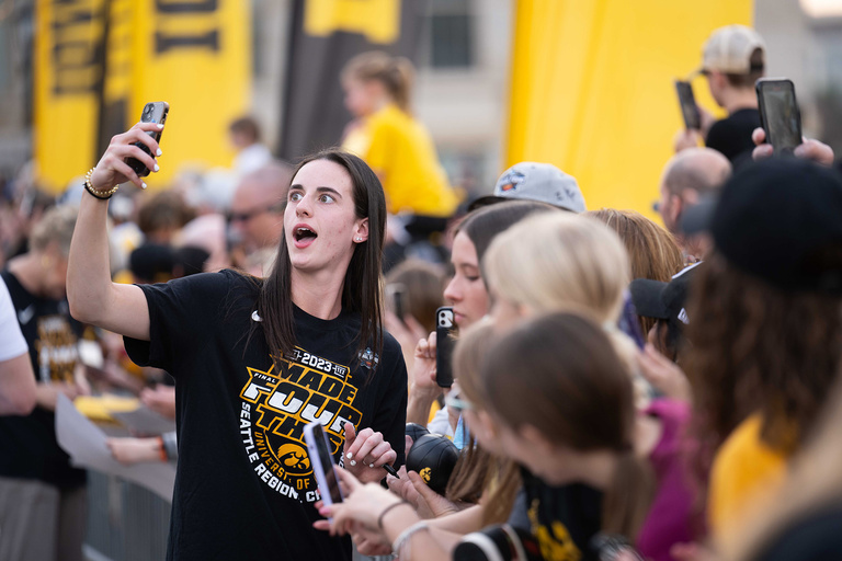 A woman posing for a selfie with a group of fans