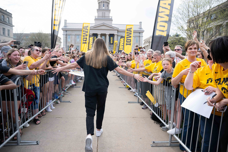 A woman walking down a row giving high-fives to a crowd