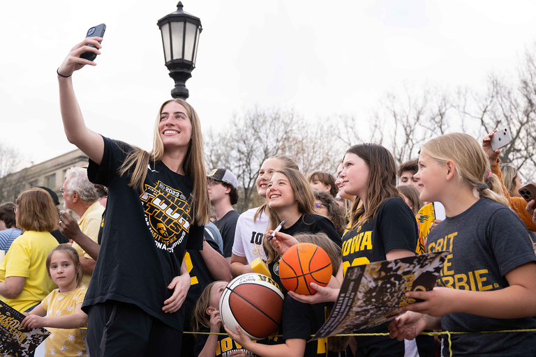 A woman taking a self with a group of young fans