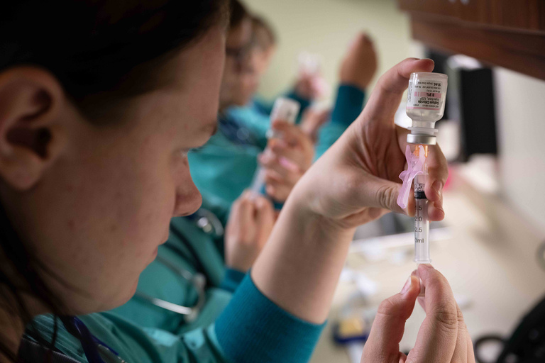 A student getting medicine out of a bottle with a syringe
