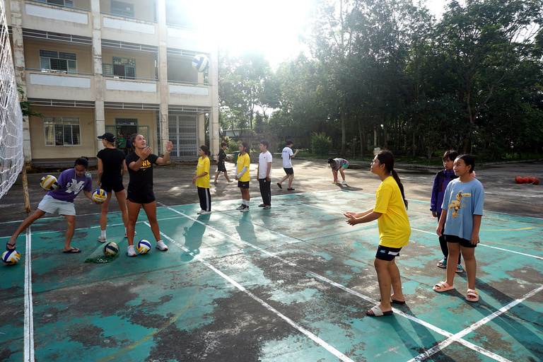 A coach practicing volleyball with some young kids