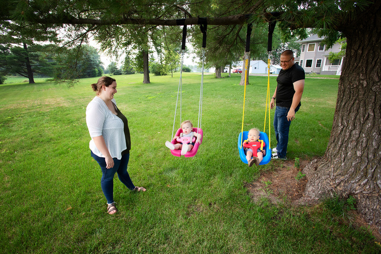 parents with twin toddlers in swings