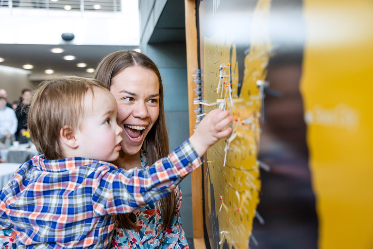 A baby helping place a pin on a map