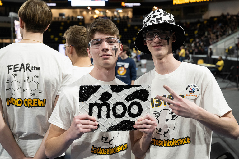 Two people posing with their teams logo