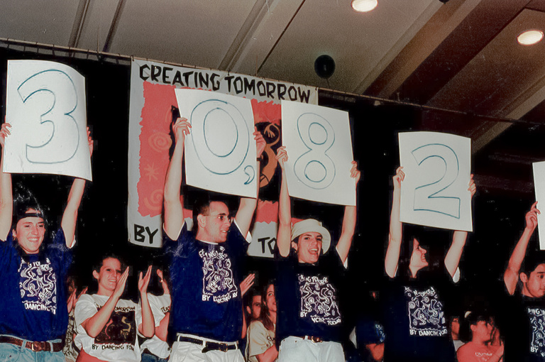 A group of volunteers holding up signs to show the amount of money raised