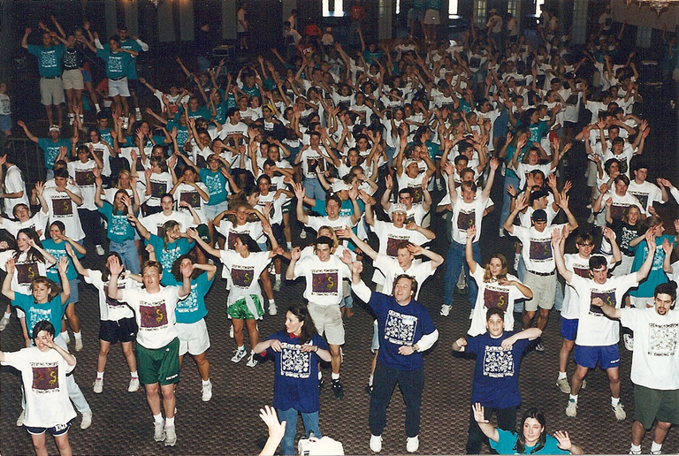 A group of people in white and blue shirts, dancing