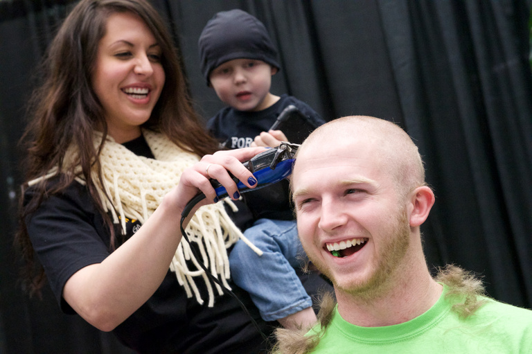 A man laughing as his head is shaved