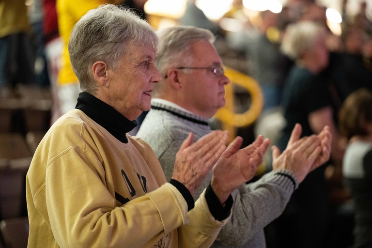 a woman and man clapping at a basketball game