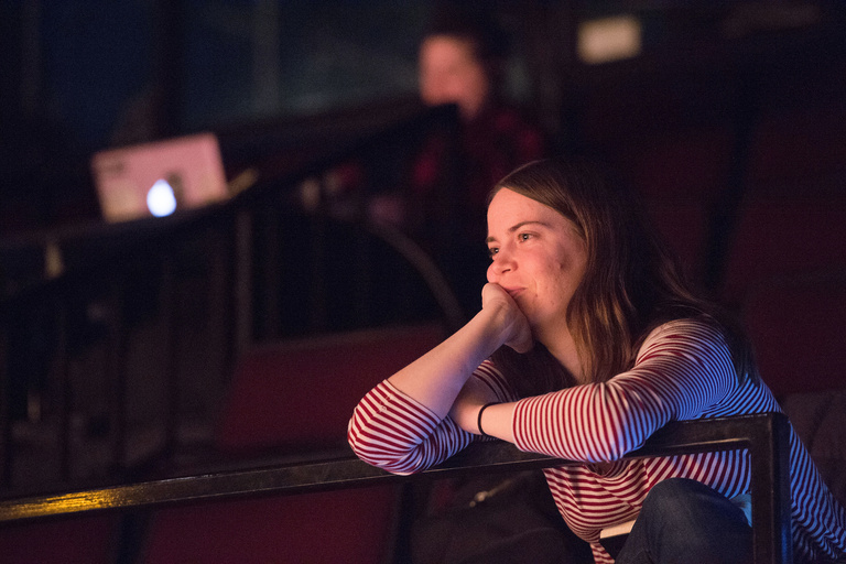 A woman leaning on a balcony looking out at the stage