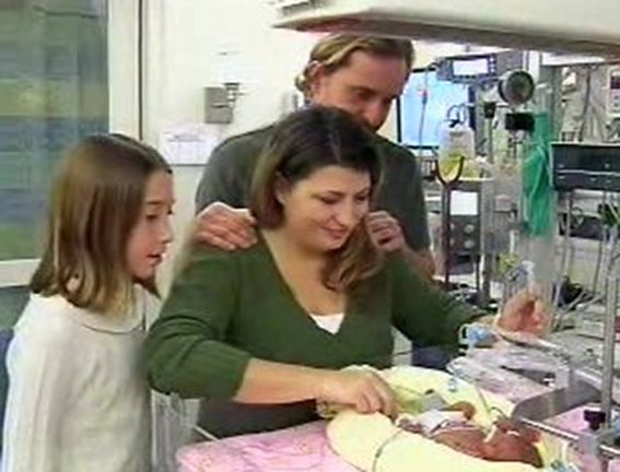 a group of people looking at a baby sleeping