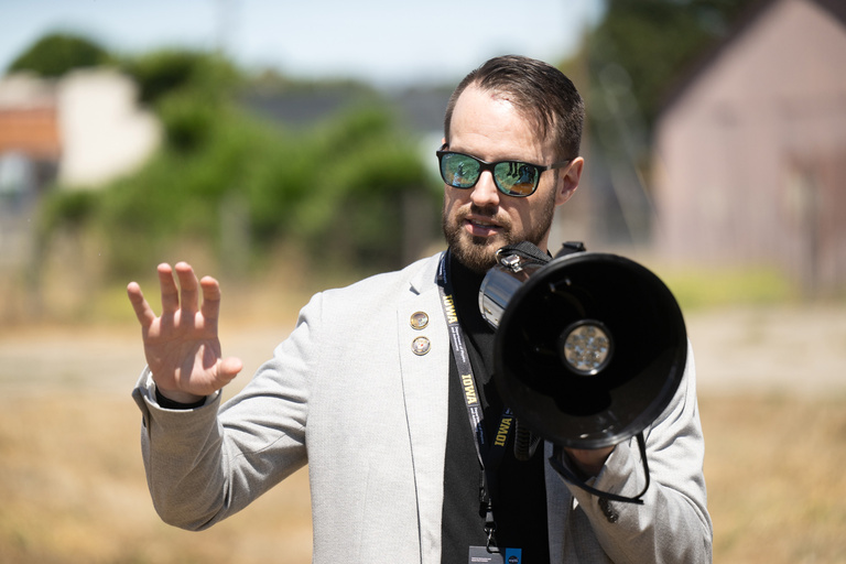 a man wearing sunglasses gestures while talking to a crowd