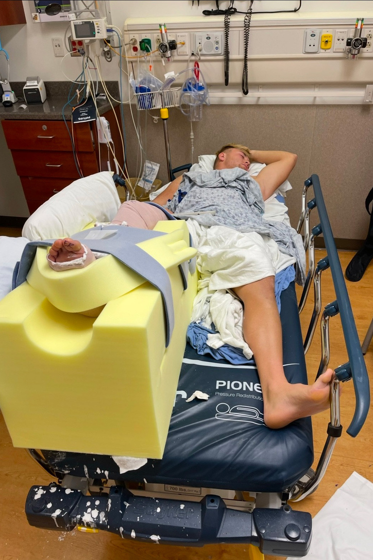 Nick Phelps lying on a hospital bed after injuring his leg