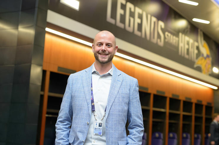 University of Iowa graduate Brandon Clemens stands inside a facility of the Minnesota Vikings, the words Legends Start Here are written on the wall behind him