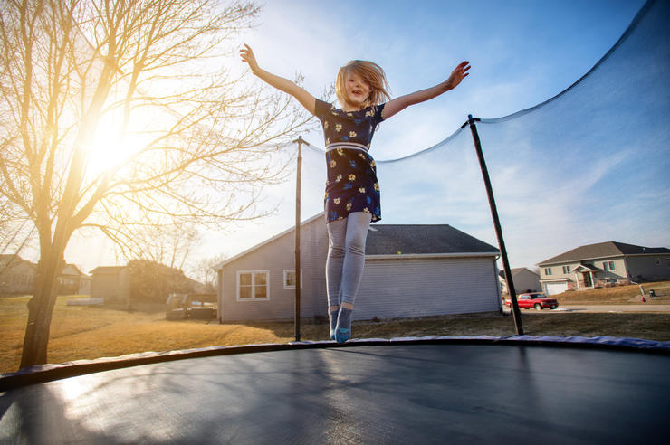young girl jumping on a trampoline as the sun begins to set