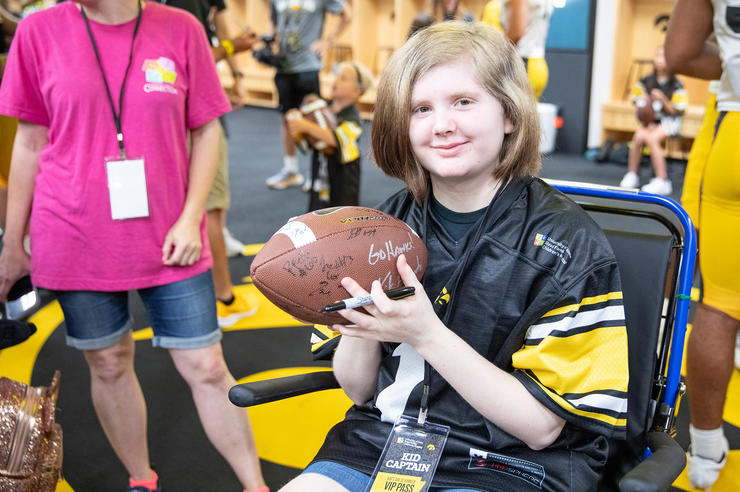Kid Captain Gabby Ford holding a football while visiting the Hawkeyes' locker room during Kids Day at Kinnick