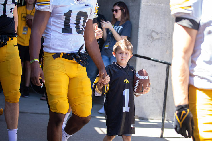 Kid Captain Lincoln Veach walking with a University of Iowa football player