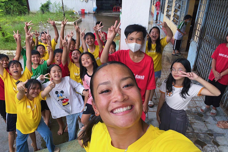 University of Iowa gymnast Adeline Kenlin posing for a selfie with youth in Vietnam