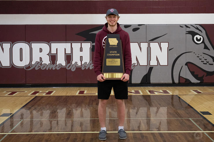 North Linn student Dylan Kurt stands in gymnasium holding state championship trophy