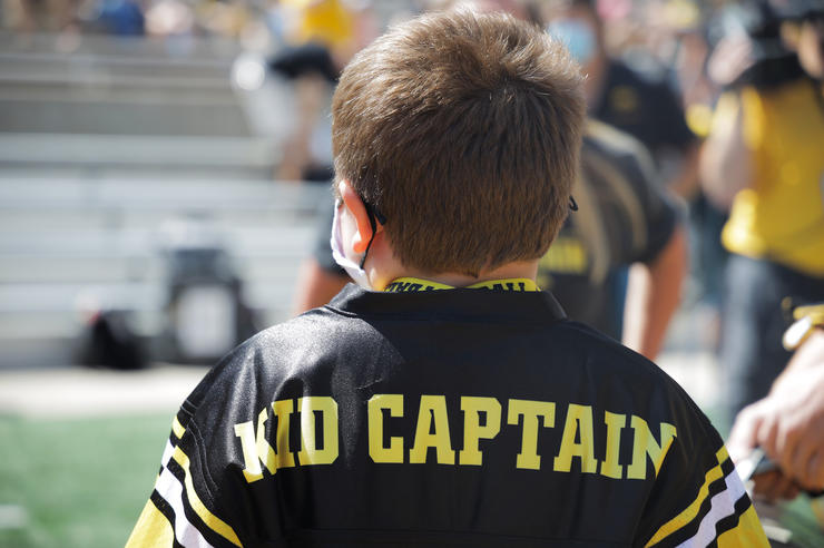 a child wearing an Iowa jersey that says Kid Captain on the nameplate