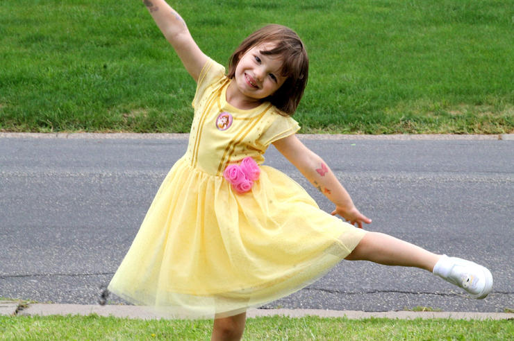 a young girl in a yellow dress poses for a photo outdoors