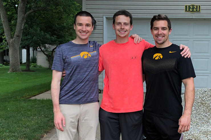 three siblings stand together in front of a garage