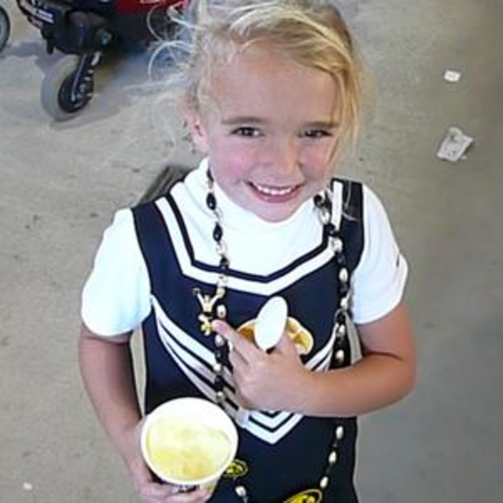 A young girl pointing to her Iowa cheerleading pin