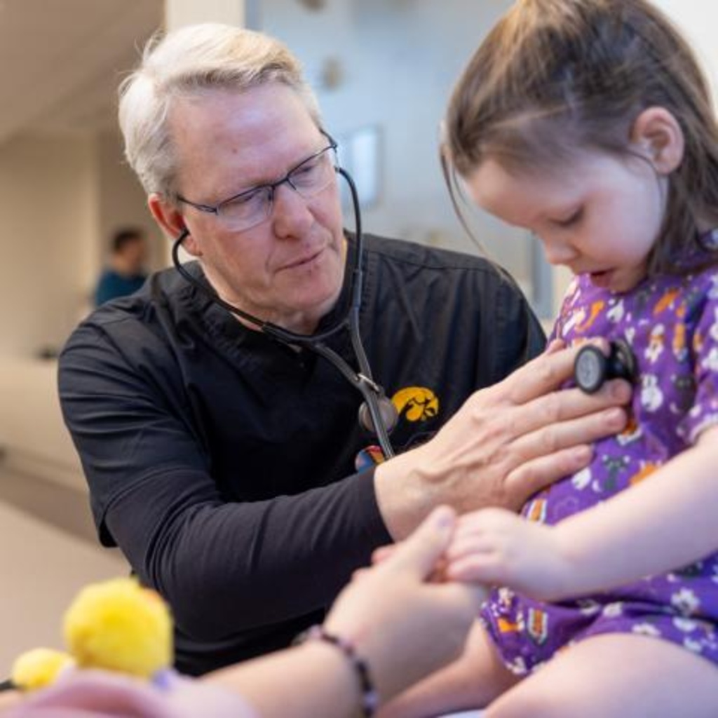 a man uses a stethoscope to listen to a child's breathing