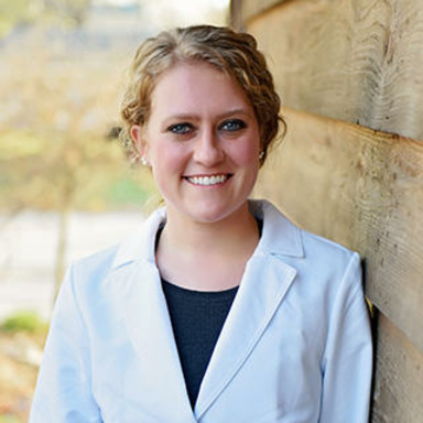 A woman leaning against a wall while smiling