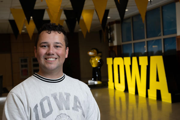 University of Iowa graduate Benton Renaud standing near a block Iowa display