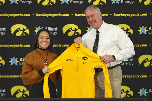 University of Iowa women's wrestling coach Clarissa Chun with athletics director Gary Barta, holding up a gold pullover with a women's wrestling wordmark