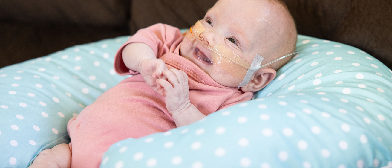 an infant girl resting on a cushion