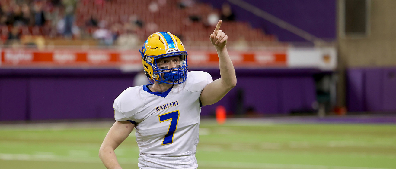 a high school football player pointing toward fans in the seating area