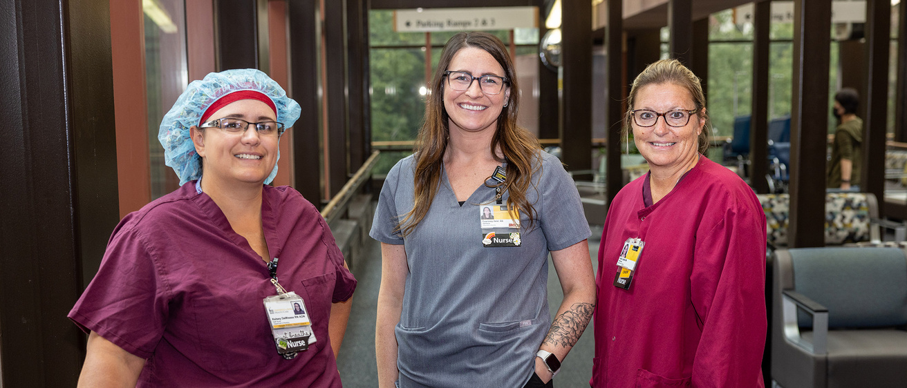 Three nurses standing in a lobby smiling