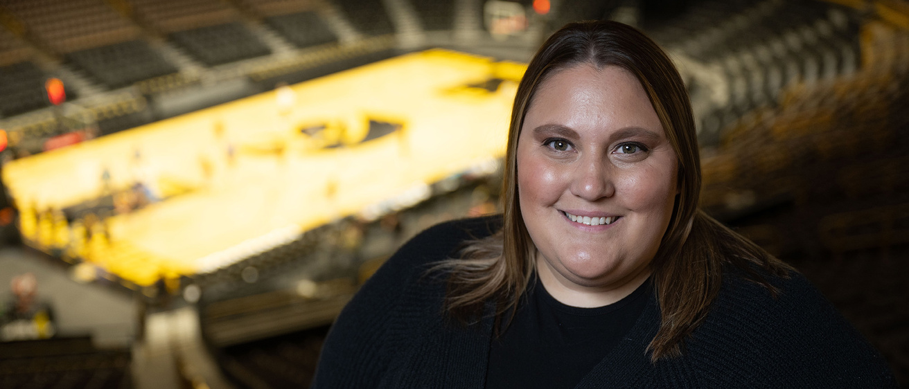 A woman smiling for a photo with a basketball court in the background
