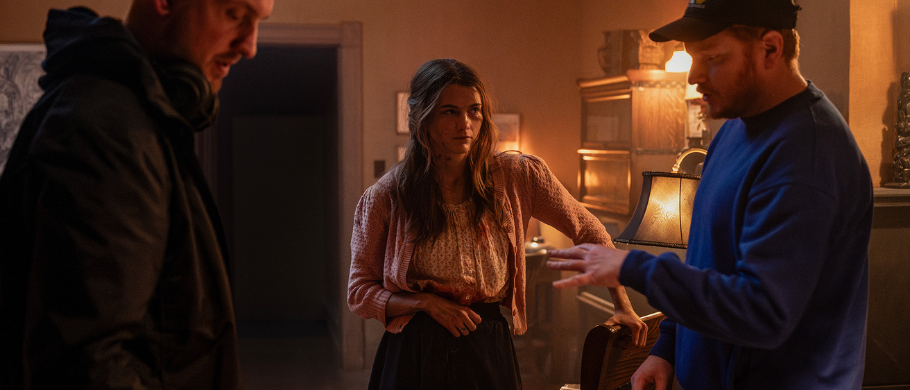 Two men directing an actress in a living room set